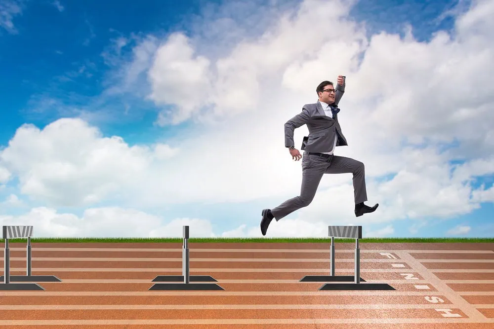 Businessman jumping over barriers in business concept