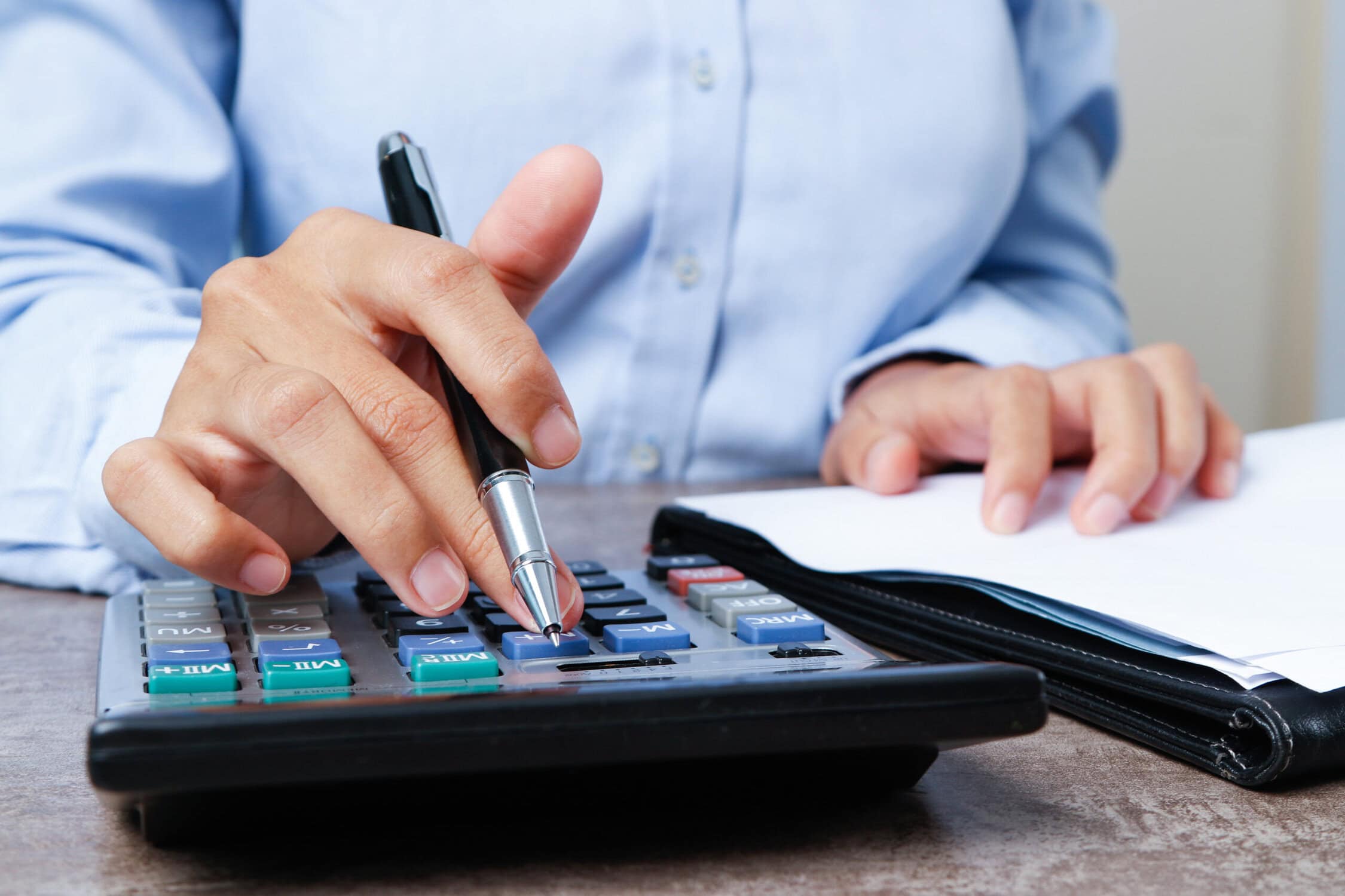 Closeup of bookkeeper using calculator. Person working with document at desk. Marketing concept. Cropped view.